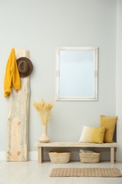 Photo of Hallway interior with wooden bench, clothes and mirror
