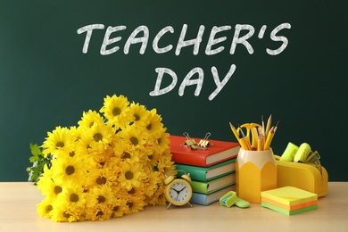 Text Teacher's Day on green chalkboard near table with bouquet and stationery 