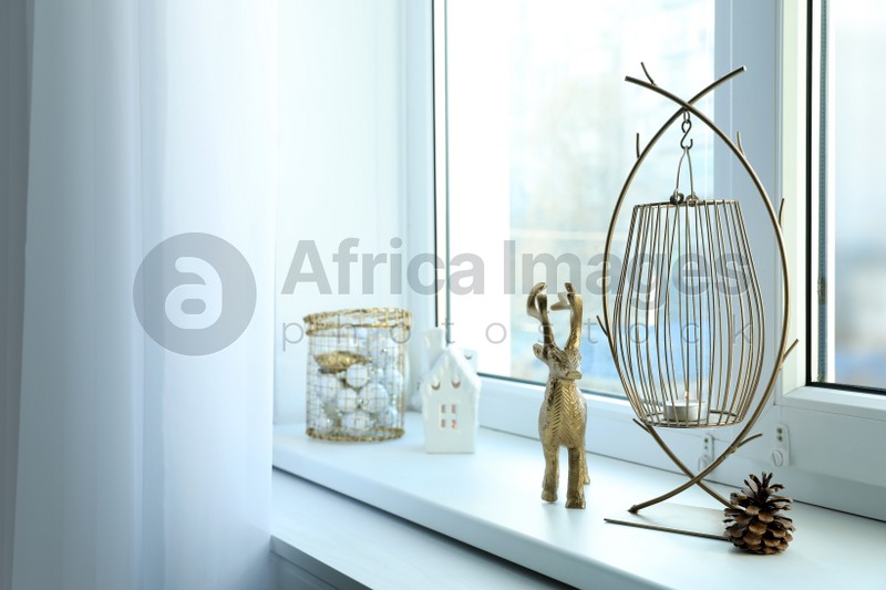 Photo of Beautiful lanterns with burning candles and Christmas decorations on window sill