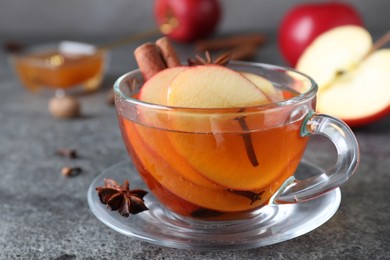 Photo of Aromatic hot mulled cider on grey table, closeup