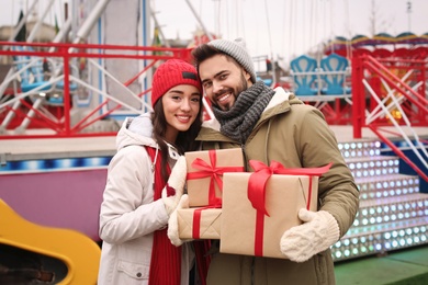 Lovely couple with Christmas presents in amusement park