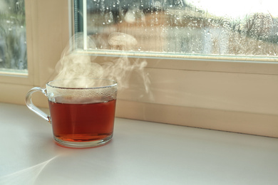 Cup of hot tea near window on rainy day.  Space for text