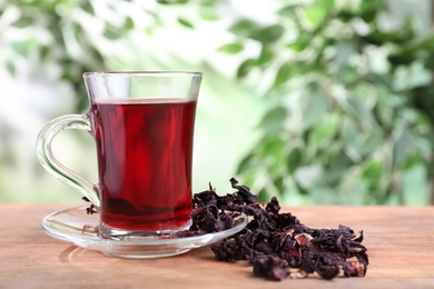 Fresh Hibiscus tea on wooden table against blurred background. Space for text
