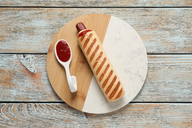 Photo of Delicious french hot dog and dip sauce on rustic wooden table, top view