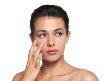 Woman applying cream under eyes on white background. Skin care