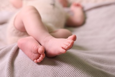 Photo of Cute newborn baby lying on light grey knitted plaid, closeup. Space for text