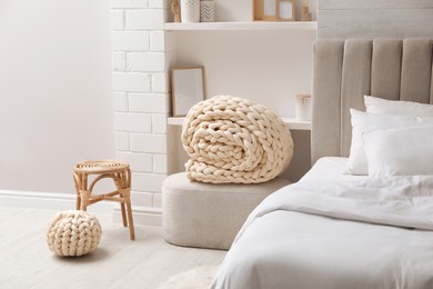 Soft chunky knit blanket and pouf in stylish room interior