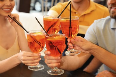 Friends with Aperol spritz cocktails resting together at restaurant, closeup