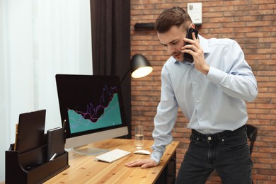 Forex trader talking on phone while working in office