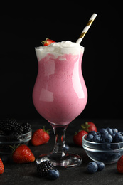 Tasty milk shake with whipped cream and fresh berries on black slate table