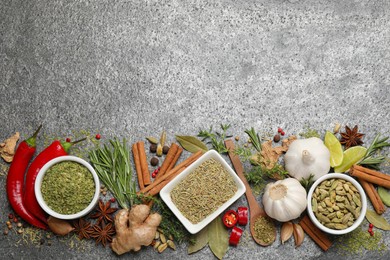 Flat lay composition with different natural spices and herbs on grey table, space for text