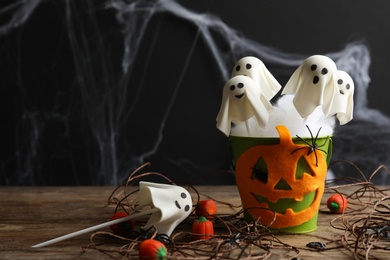 Ghost shaped cake pops on wooden table, space for text. Halloween treat