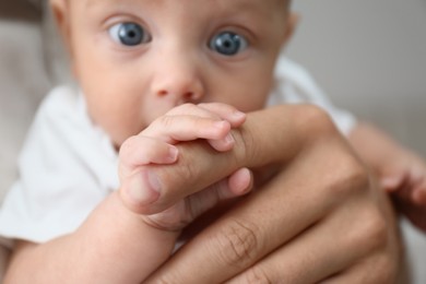 Father with his cute baby at home, focus on hands