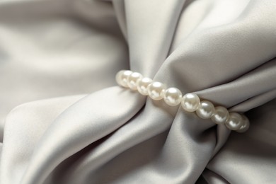 Elegant bracelet with pearls on grey silk, closeup