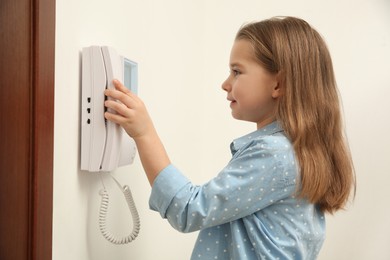 Cute little girl answering intercom call indoors