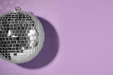 Bright shiny disco ball on violet background, top view. Space for text