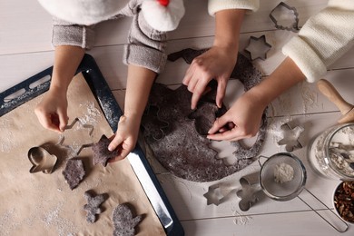 Mother and child making Christmas cookies at white wooden table together, top view
