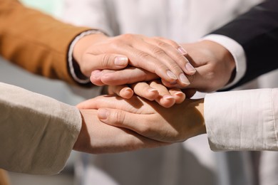 Group of people holding hands together indoors, closeup. Unity concept