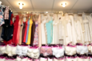 Blurred view of female nighties on hangers in underwear shop