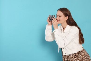 Photo of Young woman with camera taking photo on light blue background, space for text. Interesting hobby
