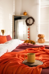 Hot drink on bed with orange blanket at home. Idea for decor in autumn colors