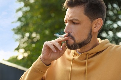 Photo of Handsome mature man smoking cigarette outdoors on sunny day