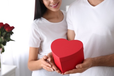 Lovely couple with gift box at home, closeup. Valentine's day celebration