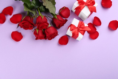 Beautiful red roses and gift boxes on violet background, flat lay with space for text. Valentine's Day celebration