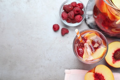 Photo of Flat lay composition of delicious peach lemonade with soda water and raspberries on grey table, space for text. Fresh summer cocktail