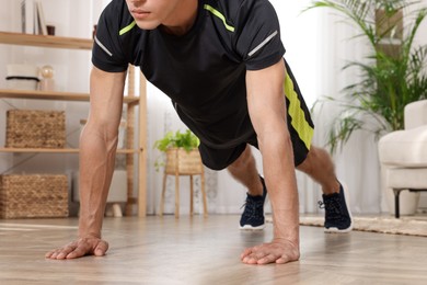 Man doing high plank exercise on floor at home, closeup