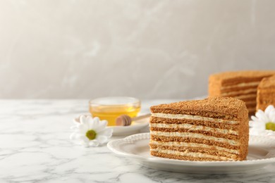 Slice of delicious layered honey cake served on white marble table. Space for text