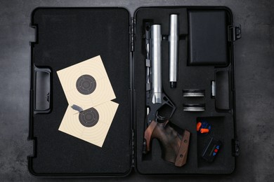 Case with sport pistol and accessories on black table, top view. Professional gun