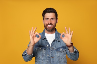 Photo of Bearded man doing ok gesture on orange background