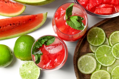 Photo of Tasty watermelon drink with lime and fresh ingredients on white table, flat lay