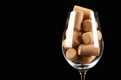 Glass full of wine corks on black background, closeup. Space for text