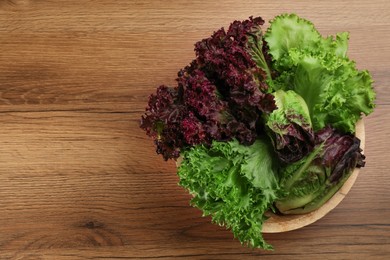 Photo of Different sorts of lettuce on wooden table, top view. Space for text