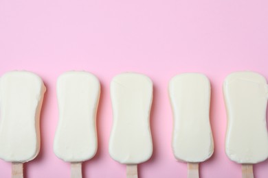 Photo of Glazed ice cream bars on pink background, flat lay. Space for text