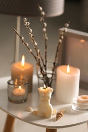 Beautiful body shaped candles and willow bouquet on table indoors