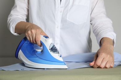 Photo of Woman ironing clean shirt on board, closeup