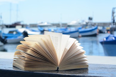 Open book on wooden bench near sea