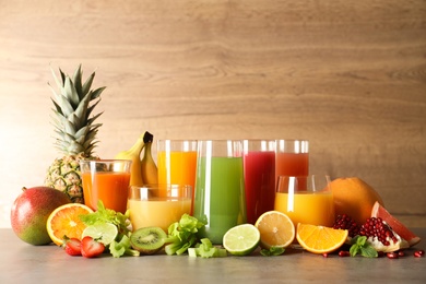 Glasses with different juices and fresh fruits on table