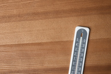 Weather thermometer on wooden table, top view. Space for text