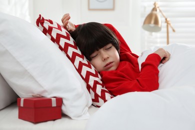 Cute little boy sleeping in bed, gift box under pillow. Saint Nicholas day tradition