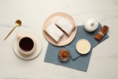 Photo of Delicious strudel with powdered sugar served on white marble table, flat lay