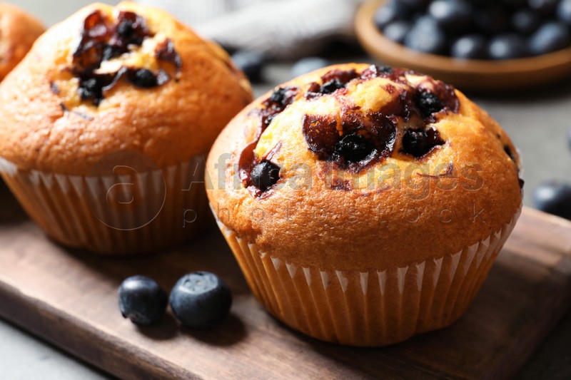 Photo of Tasty blueberry muffins on wooden board, closeup view