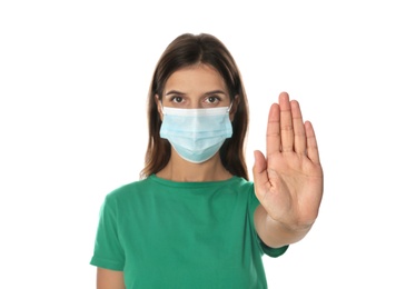Woman in protective mask showing stop gesture on white background. Prevent spreading of coronavirus