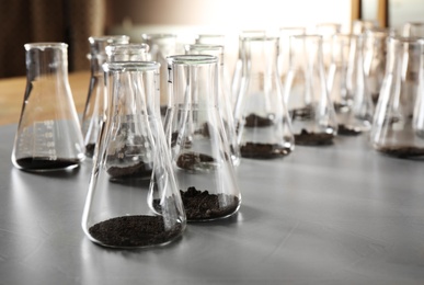 Glassware with soil samples on grey table. Laboratory research