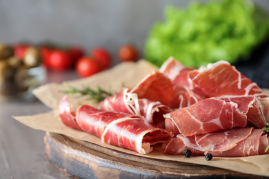 Slices of tasty prosciutto on grey table, closeup