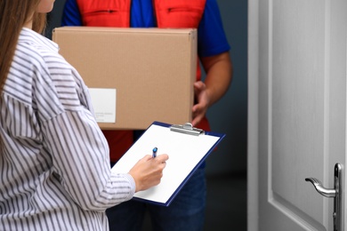 Woman signing for delivered parcel on doorstep, closeup