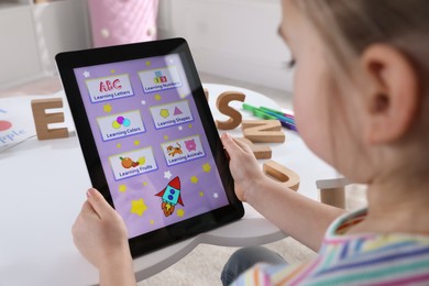 Little girl learning English with tablet indoors at online lesson, closeup